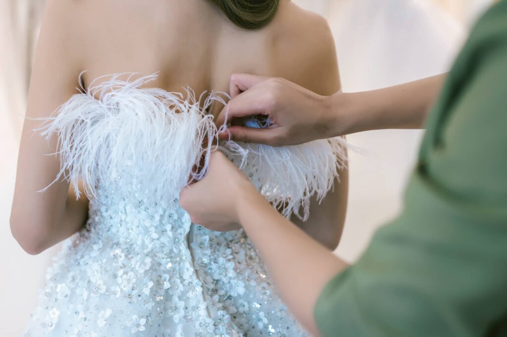 Seamstress adjusting the bodice of a beaded formal dress during a fitting