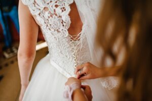Close-up of lace wedding gown corset back being adjusted during bridal fitting