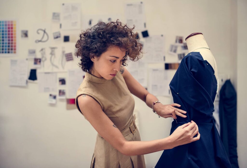 Seamstress pinning a dress on a mannequin for custom fit adjustments