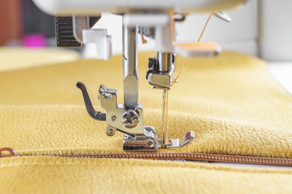 Close-up of a sewing machine stitching along a zipper during garment repair
