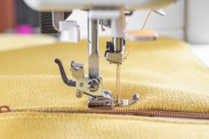 Close-up of a sewing machine stitching along a zipper during garment repair