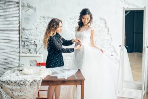 Seamstress adjusting a wedding dress during a bridal fitting appointment