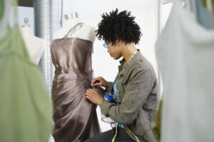 Seamstress pinning a formal dress on a mannequin for fit adjustments