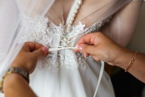 Close-up of bridal gown lace, pearl trim, and corset back during wedding dress fitting