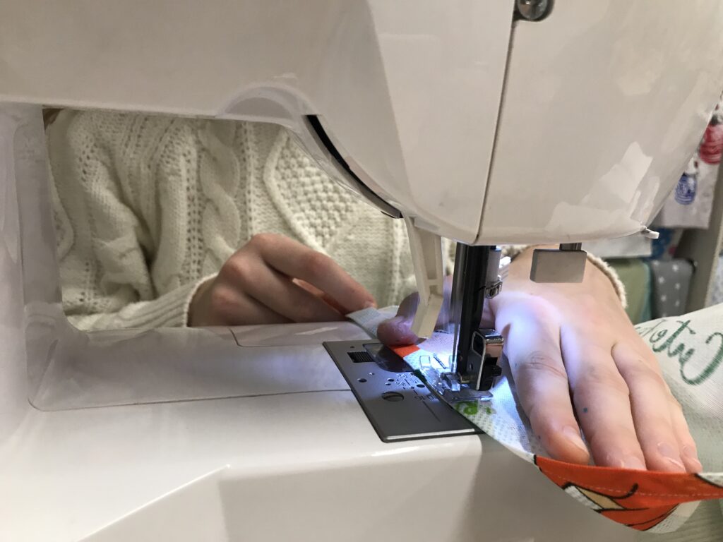 Close-up of a sewing machine stitching fabric during a hem adjustment