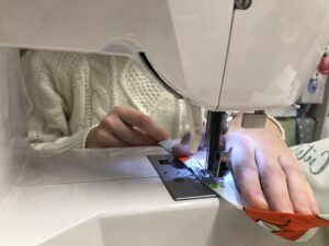 Close-up of a sewing machine stitching fabric during a hem adjustment