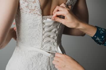 Close-up of a wedding dress bodice being adjusted during a bridal fitting