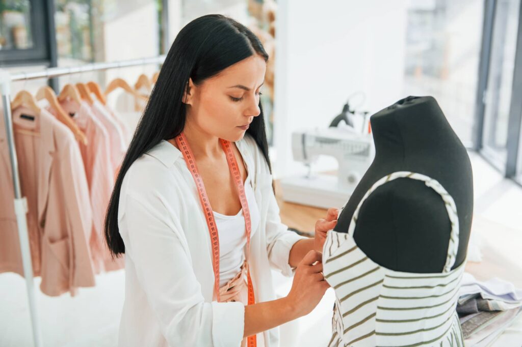 Seamstress pinning and shaping a dress on a mannequin during a fitting
