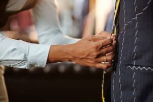 Tailor measuring and fitting a jacket on a mannequin during an alteration session